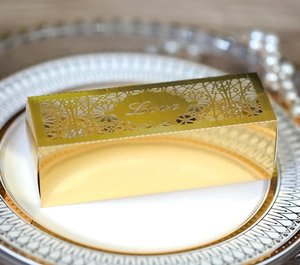 Macro detail of gold hollow-out wedding candy box featuring a laser-cut Love design