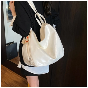Detail of creamy white patent leather hobo bag with side zipper and orange pendant