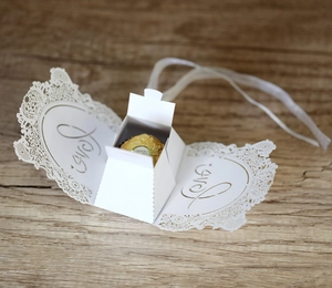 Detailed laser-cut white wedding favor box with Love pattern and silk ribbon