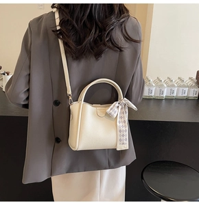 Detail of off-white lychee texture leather bucket bag with chic black and white scarf handle