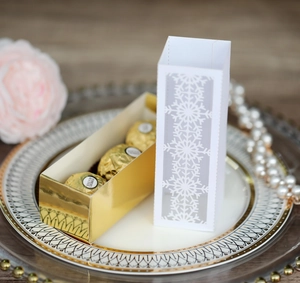 Detail of white laser-cut snowflake sleeve with gold mirror base for festive gift box