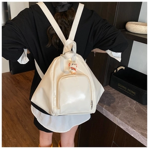 Rear view of a model wearing a white glossy patent leather backpack with cute charm