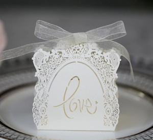 Close-up of white laser-cut wedding favor box with Love pattern and ribbon bow