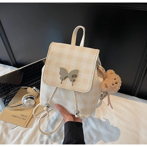 Détail du sac à dos à carreaux avec boucle papillon, breloque ours et poignée en cuir