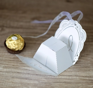 Detail of white laser-cut lace wedding favor box with Love script and purple ribbon