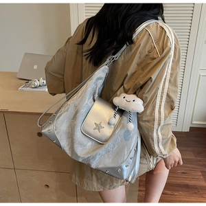 Detail of silver tote bag featuring star emblem, metallic finish and plush cloud charm