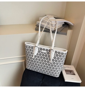 Detail of a large geometric print tote bag with white leather straps on a vintage stool