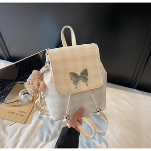 Détail du sac à dos à carreaux crème avec breloque papillon et porte-clés ours peluche