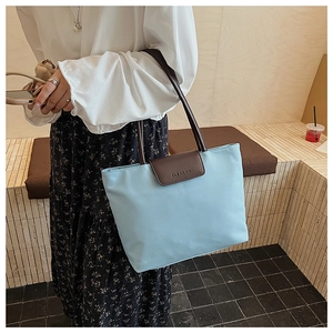 Detail of light blue tote bag with brown leather handles and embossed Cleareok logo