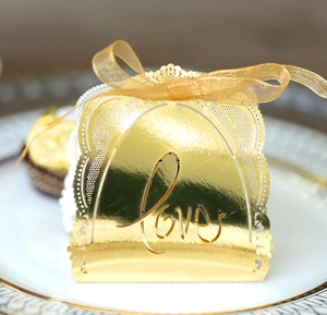 Close-up of golden laser-cut LOVE candy box with mirror finish and organza ribbon