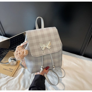 Détail du sac à dos argenté à carreaux avec papillon en métal et pendentif ours en peluche