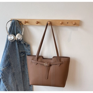 Detail of brown litchi textured leather tote bag with white contrast stitching accents