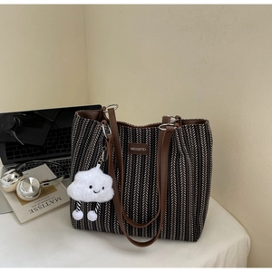 Close-up of chevron canvas tote bag with leather straps and plush cloud charm accessory