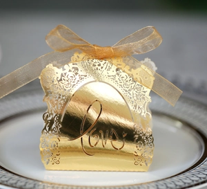 Detail showing gold laser-cut wedding favor box with Love text and organza ribbon