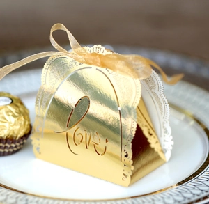 Detail view of a laser-cut gold gift box with LOVE motif and elegant ribbon tie