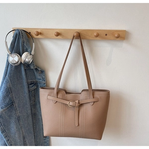 Detail of lychee pattern leather tote bag with fine white stitching and metal buckle