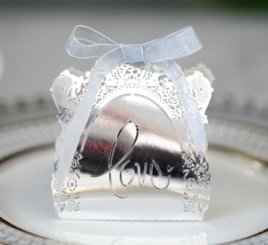 Detail of silver laser-cut candy box with Love motif and silk ribbon on a plate