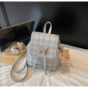 Détail du sac à dos à carreaux gris avec boucle papillon argentée et petit ours
