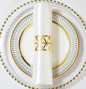 Macro detail of golden geometric triangle napkin ring on a white silk napkin