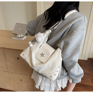 Detail of white tote bag featuring star metal ornament and silver rivets on a model