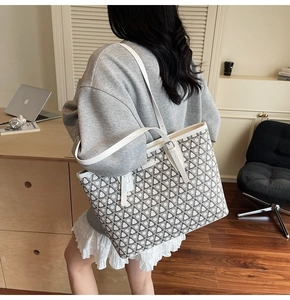 Detail view of large grey geometric tote bag being carried in a modern office setting