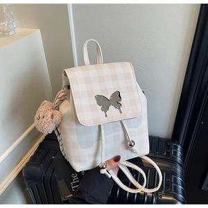 Détail d'un mini sac à dos à carreaux avec fermoir papillon et charme d'ours en peluche