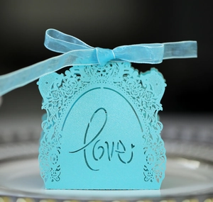 Close-up of light blue laser-cut wedding favor box with Love text and rose flower patterns
