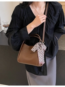 Brown bucket bag in lychee leather with plaid scarf accessory shown on model