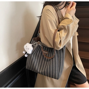 Macro detail of herringbone canvas tote bag with brown leather straps and cloud charm