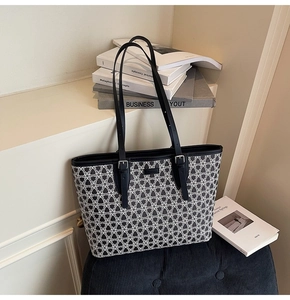 Detail of printed tote bag featuring adjustable leather straps on a velvet chair