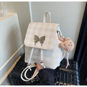 Détail du sac à dos à carreaux beige avec boucle papillon et pendentif ours en peluche