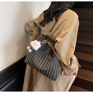 Detail of herringbone woven tote bag with brown leather strap and cloud charm on model