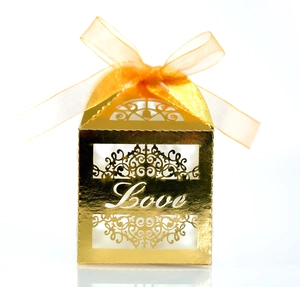 Detail of gold laser-cut wedding candy box featuring Love text and orange ribbon bow