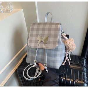 Détail du sac à dos à carreaux gris avec boucle papillon et breloque ours en peluche