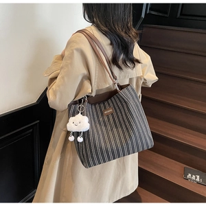 Close-up of large canvas tote bag with herringbone pattern and cloud plush pendant