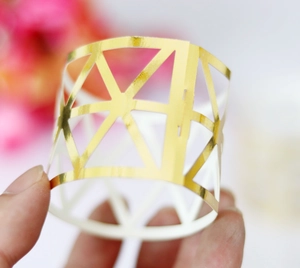 Detail showing the intricate hollow geometric gold napkin ring for wedding decor
