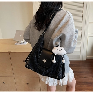 Close-up of black tote bag featuring metallic star badge and plush cloud pendant