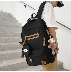 Detail view of black canvas laptop backpack with side pockets and bear keychain