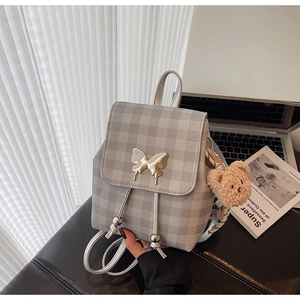 Détail d'un mini sac à dos à carreaux avec boucle papillon argentée et breloque petit ours