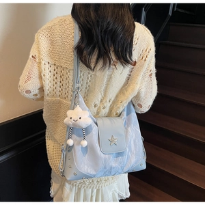 Detail of light blue pleated shoulder bag featuring star hardware and cloud plush charm