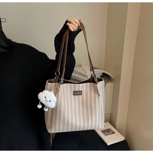 Detail of striped canvas tote bag featuring leather handles and a plush cloud charm