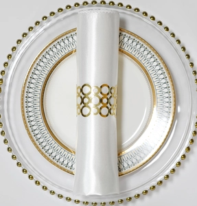 Vue détaillée du rond de serviette doré ajouré avec satin blanc sur assiettes de luxe