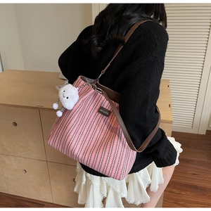 Close-up of pink and white woven tote bag with brown faux leather straps and cloud charm