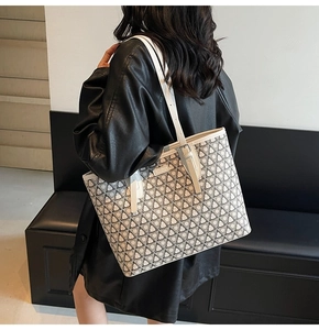 Detail of the cream tote bag with black geometric patterns worn with a black leather coat