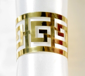 Macro d'un rond de serviette doré à motif grec avec une finition polie miroir