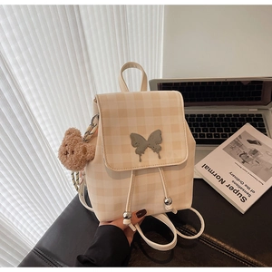 Détail du mini sac à dos beige à carreaux avec papillon argenté et breloque ours