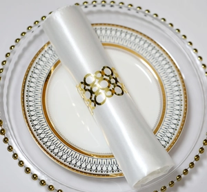 Détail d'un rond de serviette doré évidé avec cercles entrelacés sur satin blanc