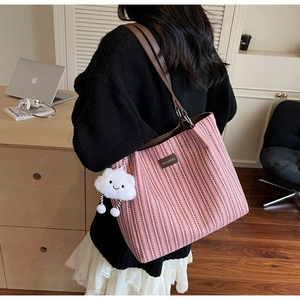 Detail showing pink striped woven tote bag with leather straps and cloud charm accessory