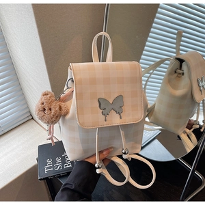 Détail du sac à dos à carreaux avec boucle papillon et charm ours en peluche