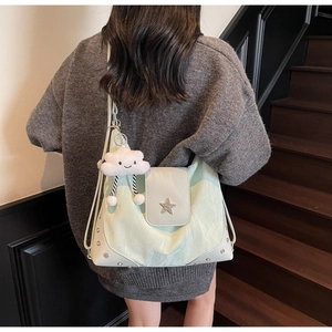 Detail view of mint green tote bag with star buckle and plush cloud charm on stair background